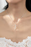 Close-up of a woman's neck wearing a delicate FASHION GO Brass Bow Pendant Necklace, against a lace top.