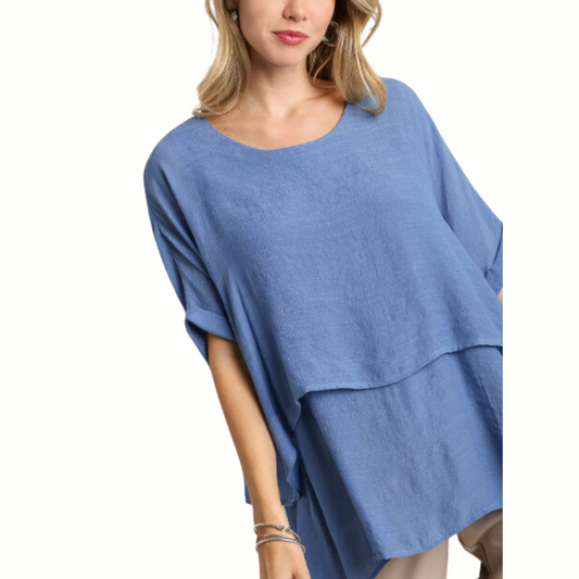 A woman modeling an Umgee Layered Tunic Top with a scooped neckline and layered design.