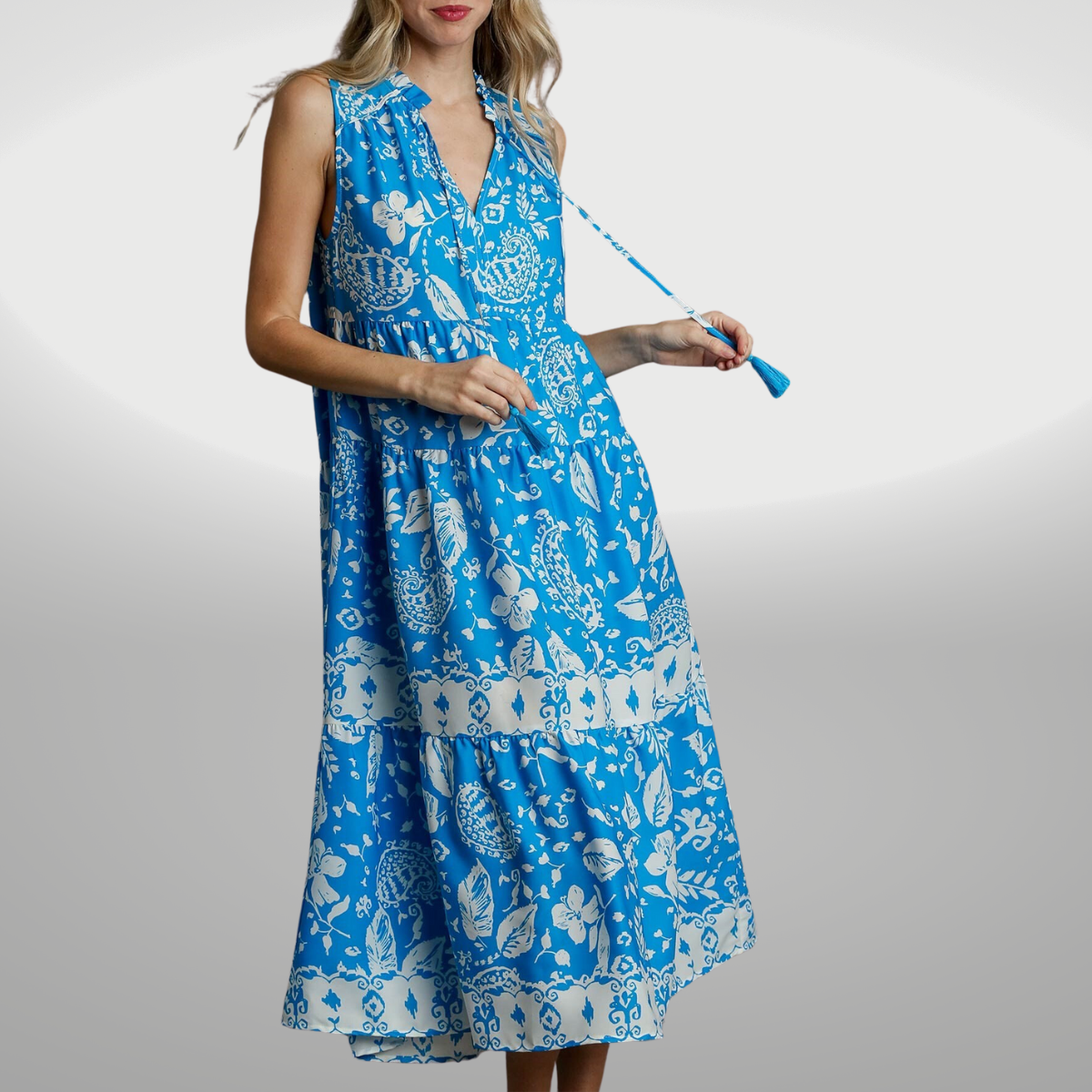 A woman wearing a FASHION GO blue and white floral sleeveless midi dress with a spring print.