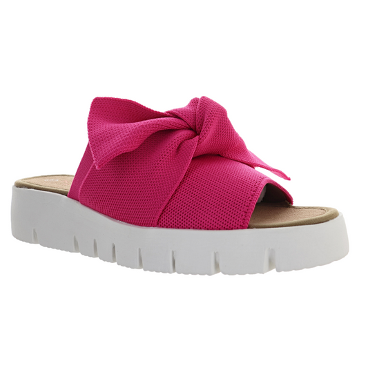 Bright pink FX Freesia Slide sandal with a bow embellishment on a white background by Bernie Mev.