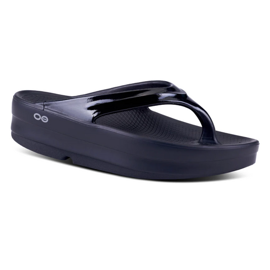 Navy blue OOMEGA THONG BLACK flip-flop with a glossy strap featuring OOfoam™ technology, isolated on a white background.