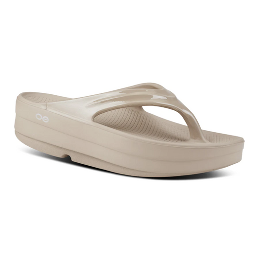Beige OOMEGA THONG NOMAD flip-flop sandal with OOfoam technology by OOFOS LLC on a white background.