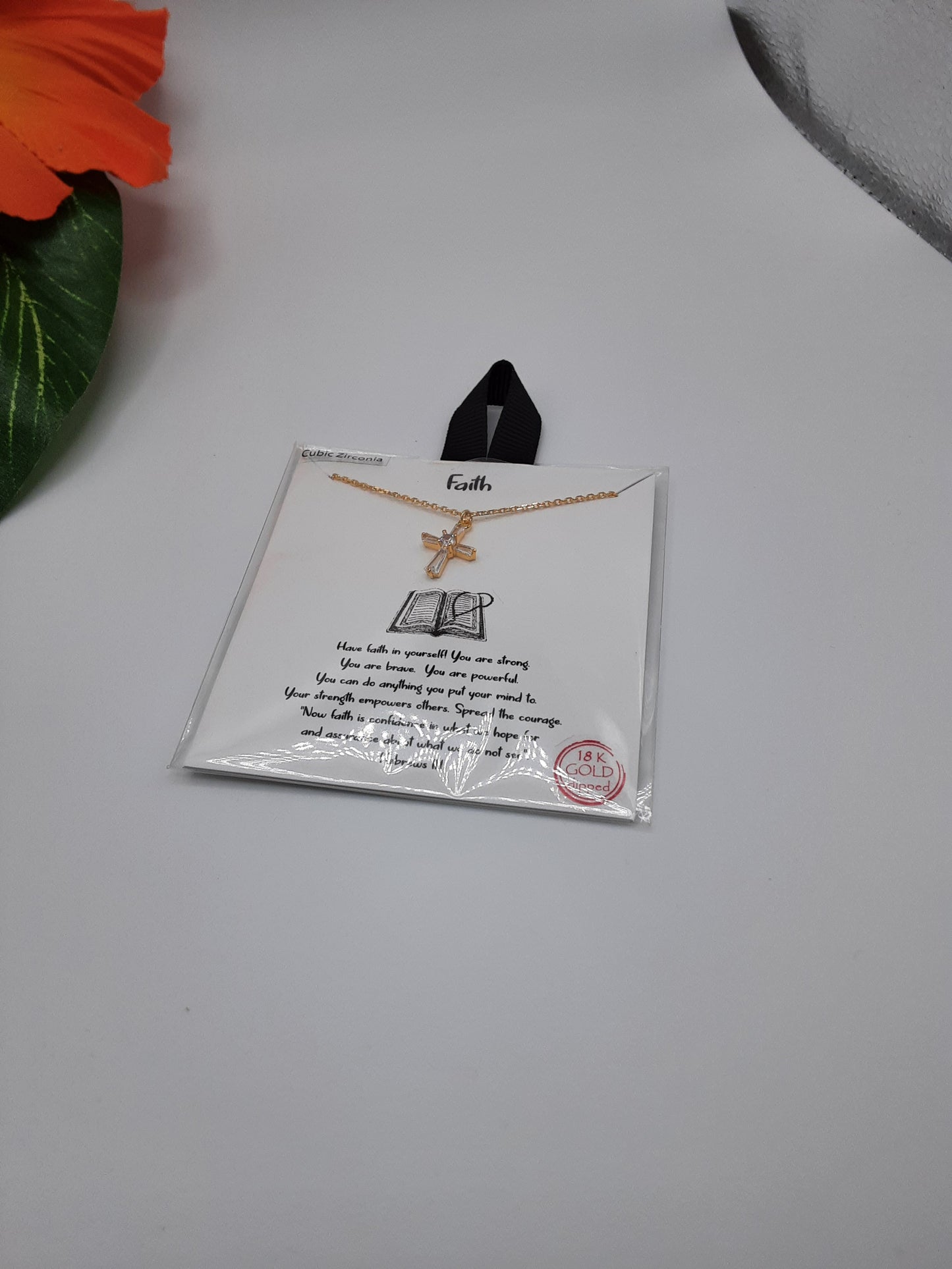 The SPECIAL EFFECTS Faith CZ Cross 16 inch Necklace is displayed on a card featuring a motivational quote, set against a white background with a partially visible orange flower in the top left corner.