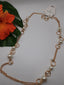 The 36" CHAIN W/PEARLS SET by SPECIAL EFFECTS features gold rings and pearl-like beads. It's visually enhanced with an orange hibiscus flower resting on a green leaf nearby. The tagged necklace is elegantly arranged against a white background.