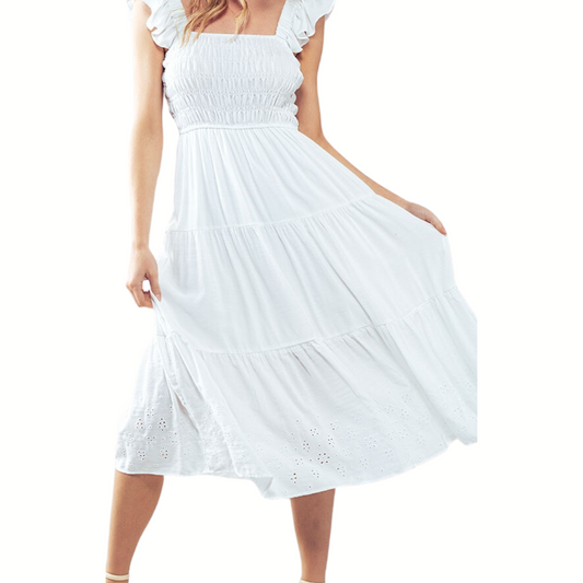 A woman wearing a white, mid-length Tiered Eyelet Hem Midi Dress from FASHION GO with ruffled sleeves and holding the skirt lightly with both hands.