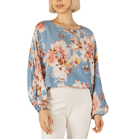 Woman wearing a Before You blue Floral Balloon Sleeve Top blouse and white pants.