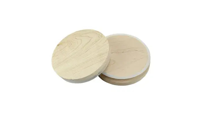 Two round wooden lids, one standing and one lying flat, promise the Stephanie Henry Candle Company's 20oz 3 Wick Soy Wax Candle with a wood lid in Coconut Lime scent waiting to fill your space.