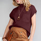 A woman with blond hair is wearing Shewin sunglasses and a Patch Pocket Ribbed Knit Short Sleeve Sweater. Her tan skirt complements the look, and she holds a brown clutch, perfect for transitional weather.