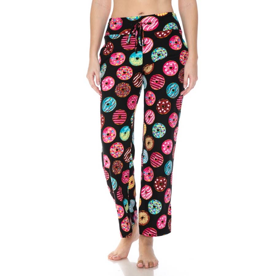 A person wears Leggings Depot's Buttery Soft Print Pajama Pants featuring a colorful donut pattern and elastic waistband, standing barefoot against a plain white background.