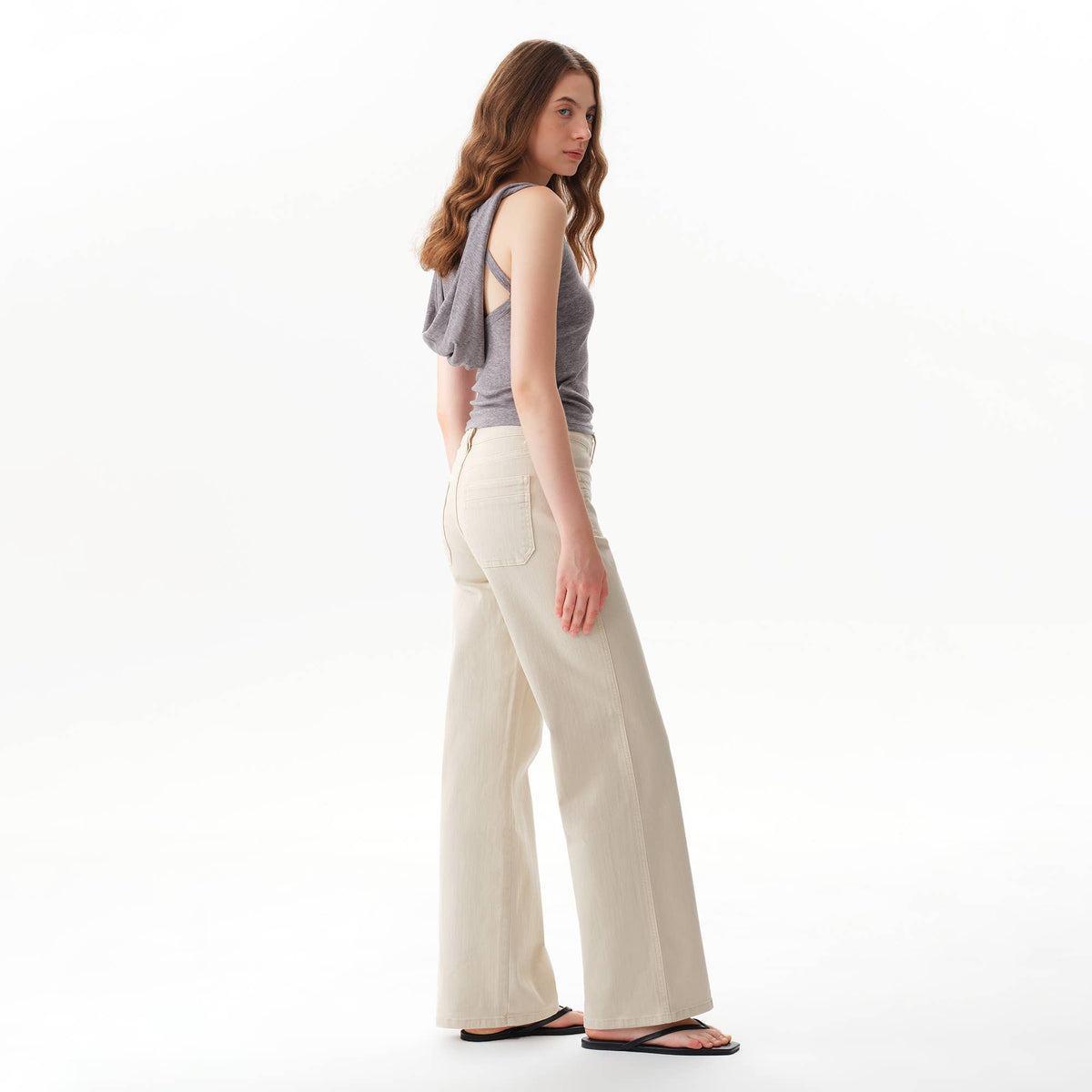 A woman in a grey tank top and Faire Off White Mid Rise Straight Pants.