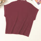 The Shewin Patch Pocket Ribbed Knit Short Sleeve Sweater in maroon, ideal for transitional weather, is arranged beside glasses, a book, and dried flowers on a light surface.