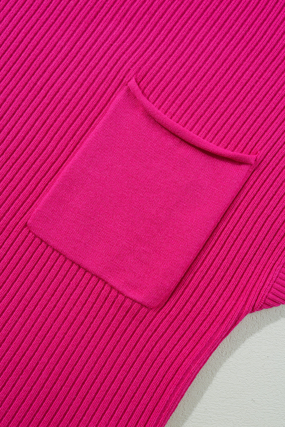 Close-up of the bright pink, ribbed knit fabric with a patch pocket on the short sleeve sweater by Shewin.