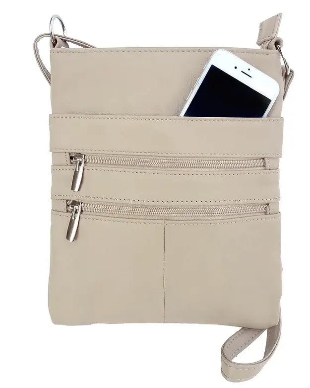 A Large cowhide leather crossbody shoulder bag by Roma Leathers, Inc. in beige, featuring two zippered pockets and an adjustable strap, holds a partially visible white smartphone in the top pocket.