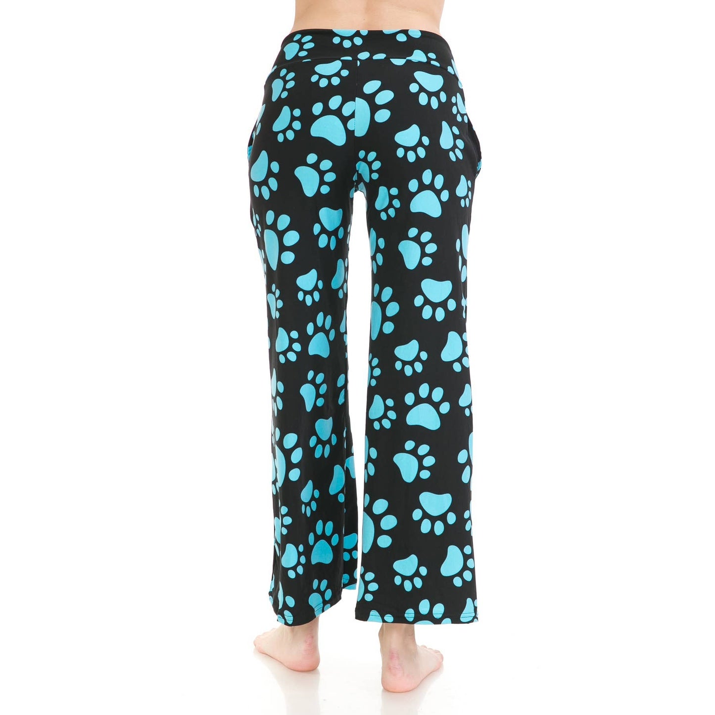 A person stands barefoot, shown from the back, in Leggings Depot Buttery Soft Print Pajama Pants—loose black pants with large blue paw prints and an elastic waistband for comfort, set against a white background.