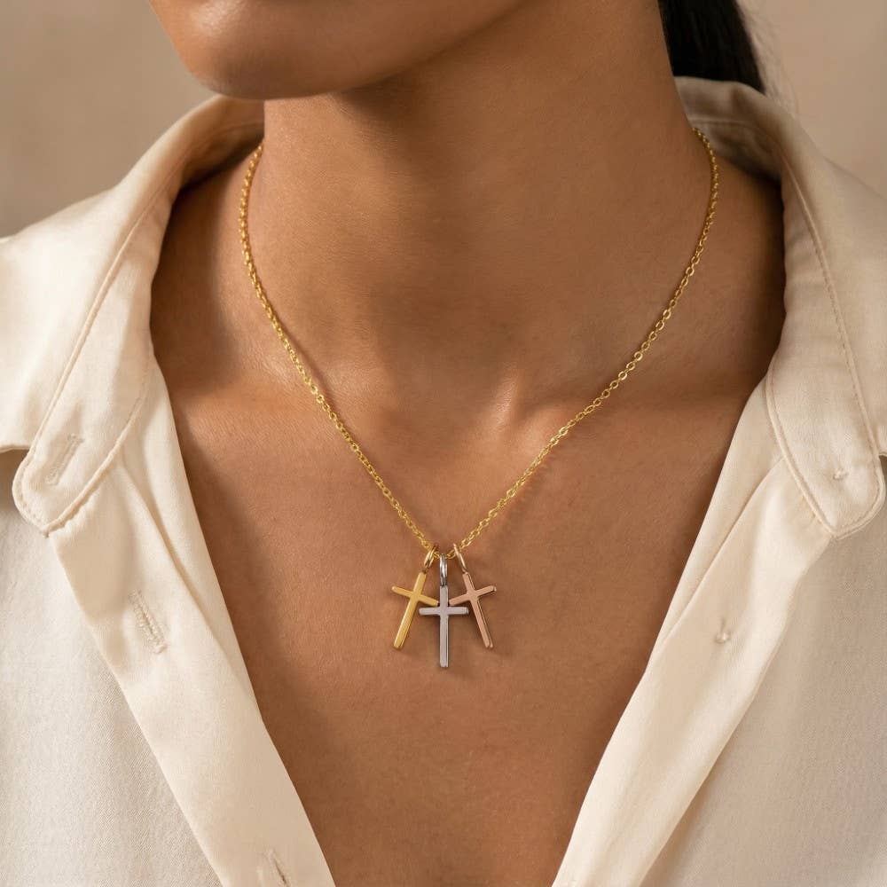 A woman wears a cream shirt and the Anarchy Street Triple Cross Pendant Necklace, featuring gold, silver, and rose gold dipped crosses.