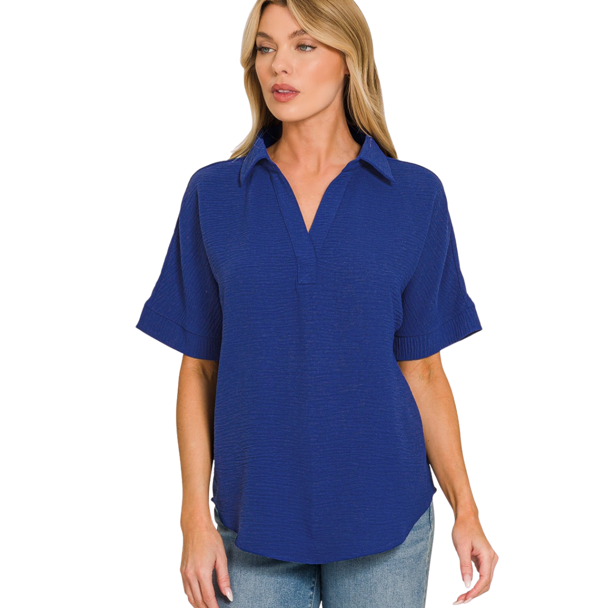 A woman wears the Flipflops & Whatnots Woven Airflow Collared Top in royal blue with short sleeves and a V-neck, paired with light blue jeans. This lightweight summer blouse ensures all-day comfort against a plain background.