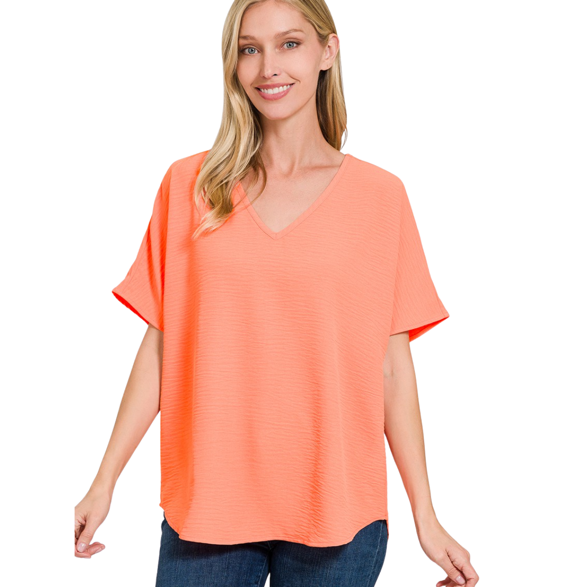 A woman smiles against a white background, wearing the Zenana V-Neck Airflow Shirt Sleeve Top with blue jeans.