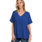 A woman wearing the Zenana V-Neck Airflow Shirt Sleeve Top with jeans stands against a white background.