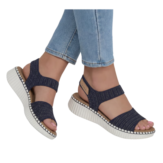 Wearing the Skechers Summertime Imspo Sandal in Navy by SKECHERS USA INC with light blue jeans on a white background—a stylish, comfortable choice for everyday walking.