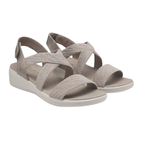 A pair of SKECHERS Arya Very Midful Low Wedge Heel Sandals in light beige, featuring open toes and crisscross elastic straps, is displayed on a white background.