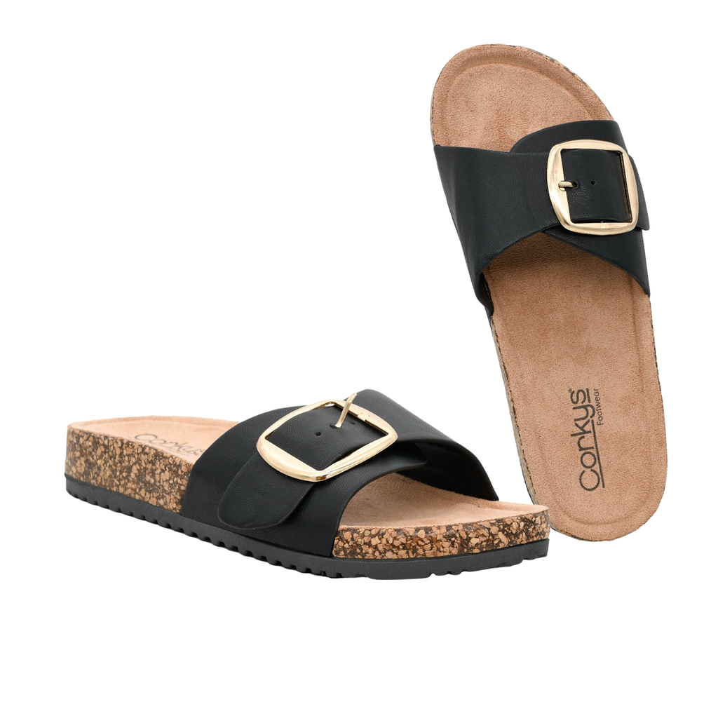 The Road Trip Buckle Slide Sandal by CORKY'S FOOTWEAR INC features black statement buckles, cork footbeds, and tan insoles, shown on a white background.