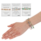 A hand wears three Flipflops & Whatnots Blessing Bracelets - Assorted, each matching the Colors of Faith cards labeled “GRATITUDE,” “FAITH,” and “BLESSED,” displayed above with Bible verses.