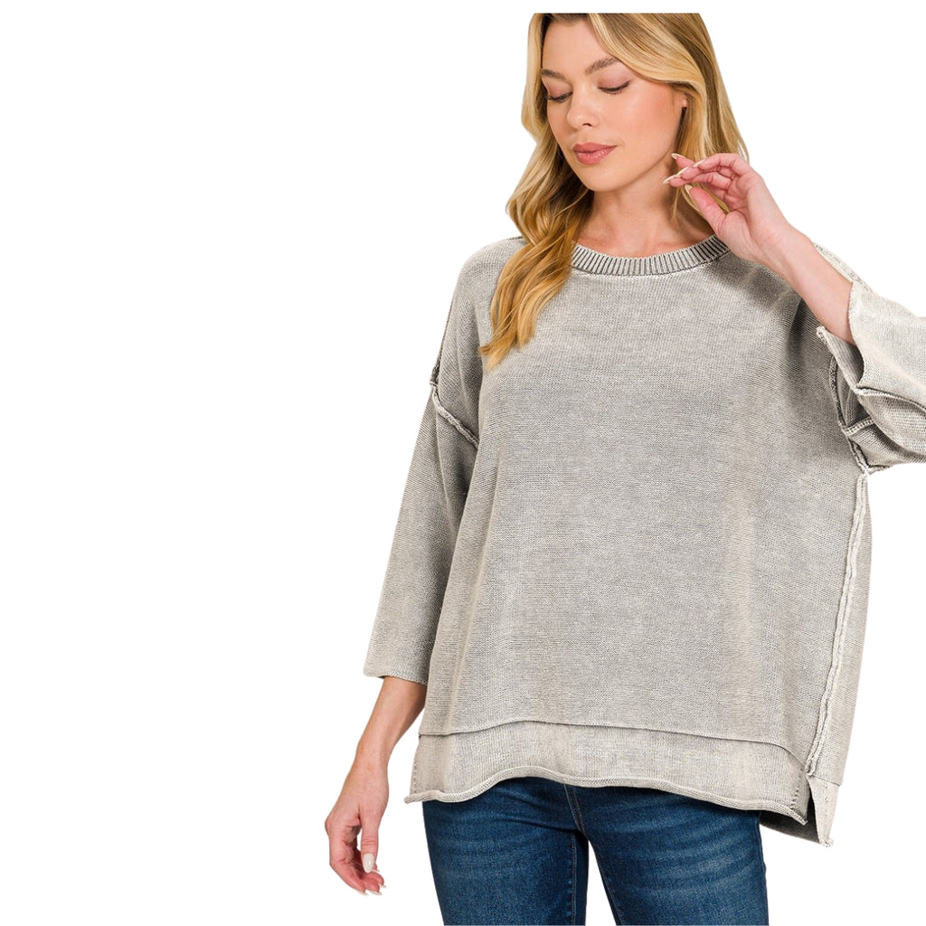 A person wears a FASHION GO Women’s Washed Cotton Boxy Sweater, featuring a grey, boxy silhouette with three-quarter-length sleeves, drop shoulders, and an asymmetrical hem with exposed seam detailing.