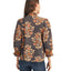 A woman is seen from behind wearing the FASHION GO Embroidered Smocking Detail Floral Top, a long-sleeved dark blouse with an orange floral print, ruffled cuffs, and embroidered smocking, paired with blue jeans.