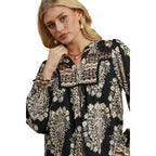 Woman wearing the Boho Paisley Blouse by Umgee, featuring black balloon sleeves with floral and geometric patterns, against a white background.