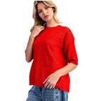 A woman wears an eesome Marled Knit Cherry Red Sweater, a cherry red, short-sleeved marled knit sweater.