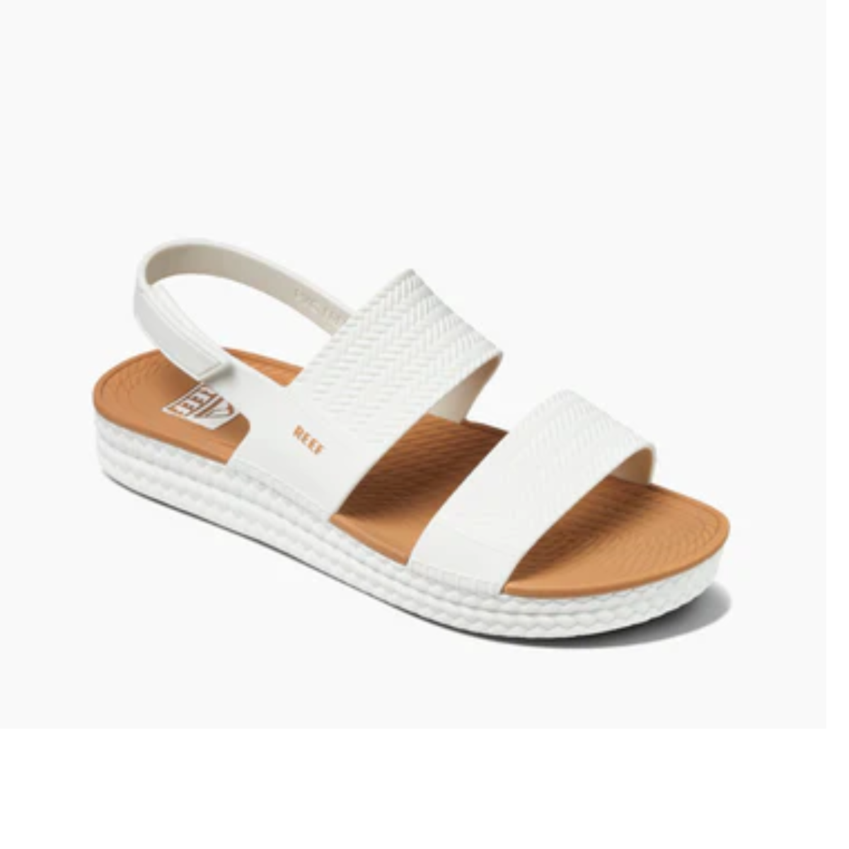 A Water Vista in White by REEF with two wide, textured straps across the top and a Velcro backstrap. The sole is thick with a dual density footbed, featuring a tan insole and the brand name "REEF" clearly visible. Main image