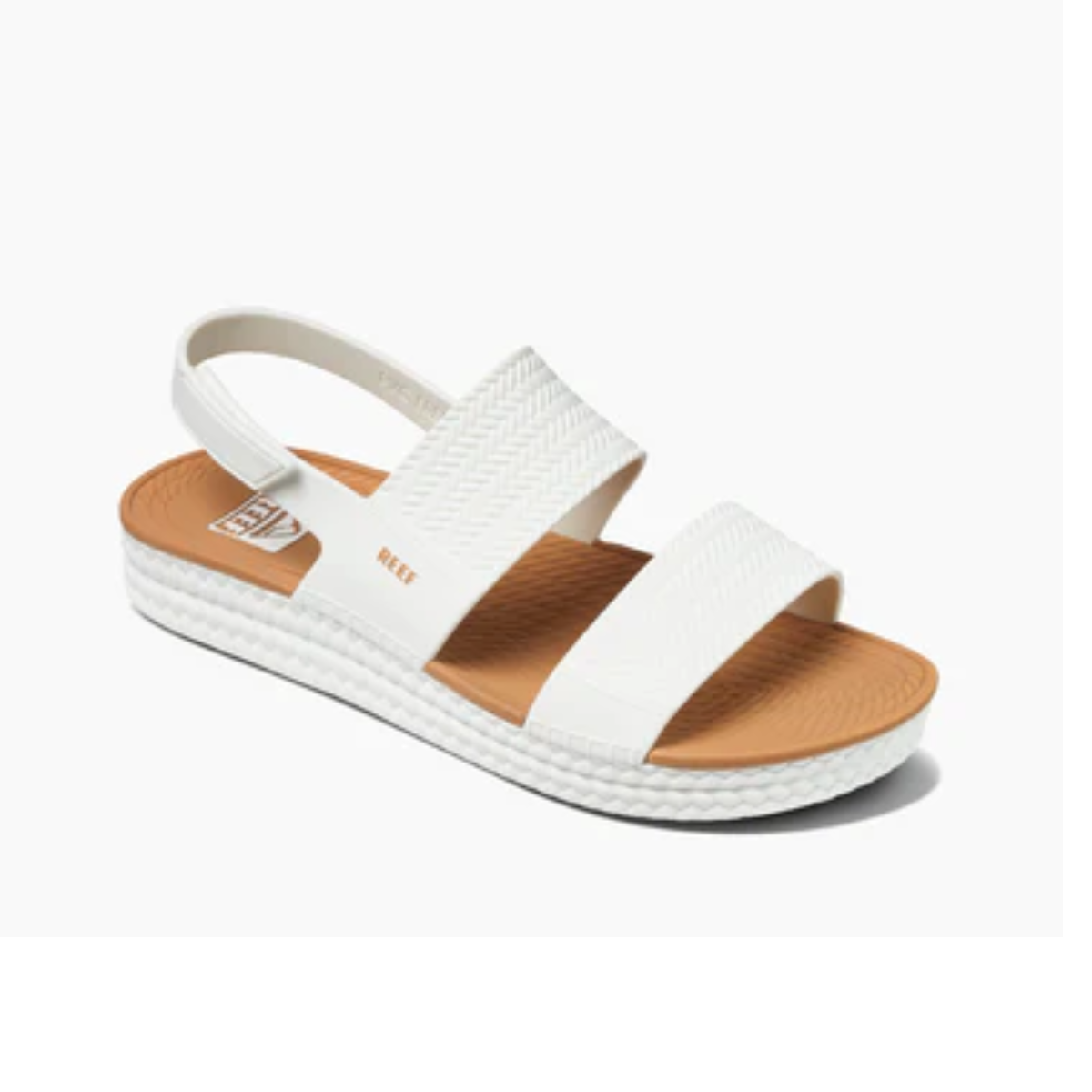 A Water Vista in White by REEF with two wide, textured straps across the top and a Velcro backstrap. The sole is thick with a dual density footbed, featuring a tan insole and the brand name "REEF" clearly visible.