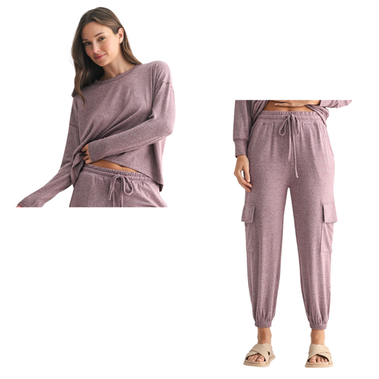 A woman wears the Mono B Brushed Hacci Cargo Lounge Pant Set in Plum, featuring a long sleeve top and jogger-style cargo pants with pockets and a drawstring waist, paired with beige slide sandals.