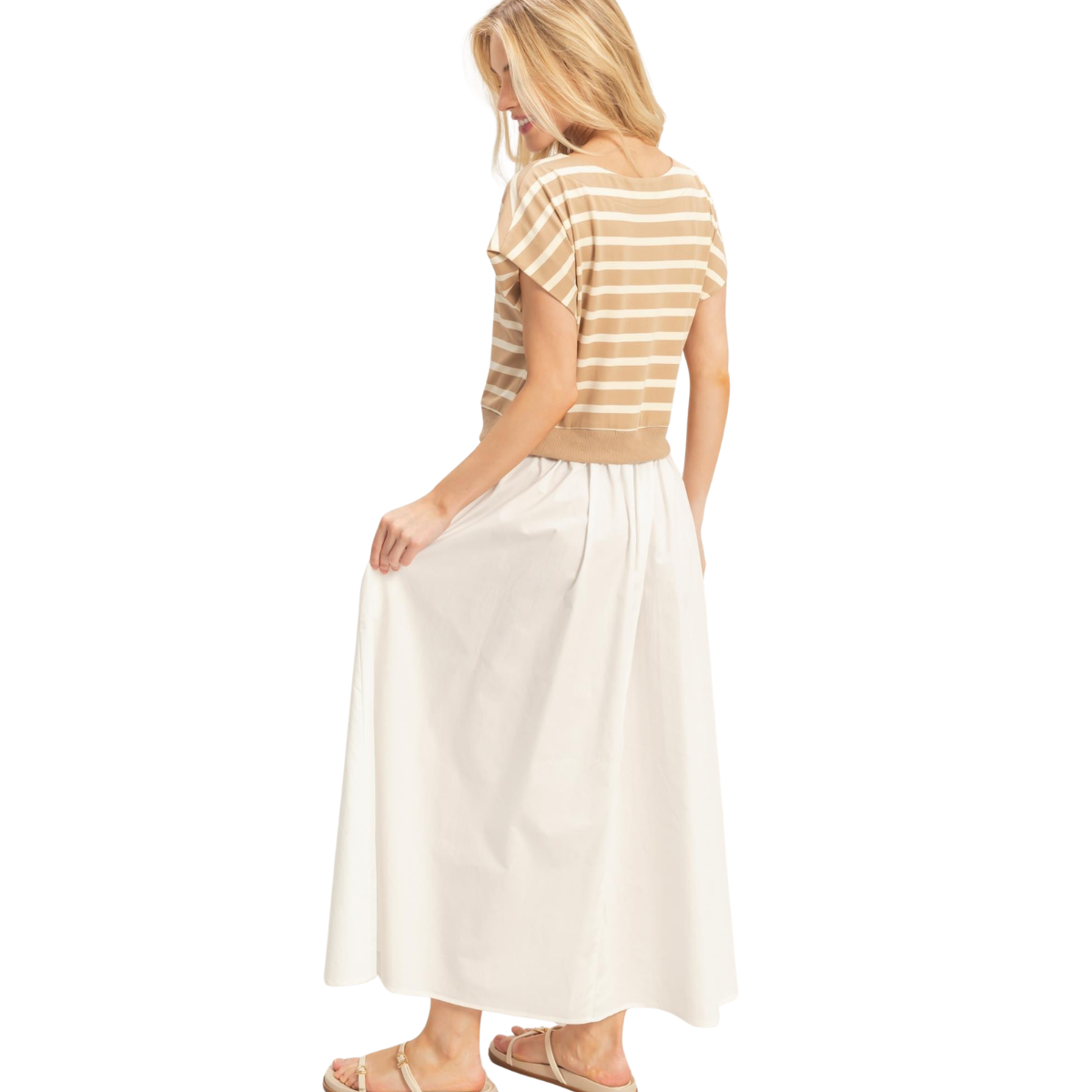 A woman wears Fashiongo’s Striped Short Sleeve Midi Dress in relaxed beige and white, standing with her back to the camera and gently holding her skirt. Main image