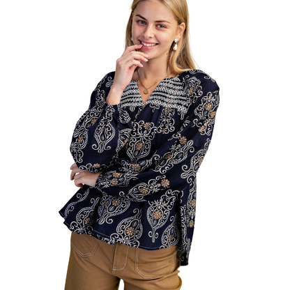 A person wears the FASHION GO Printed Balloon Sleeve V-neck Blouse and brown pants, smiling with one hand on their chin against a white background.