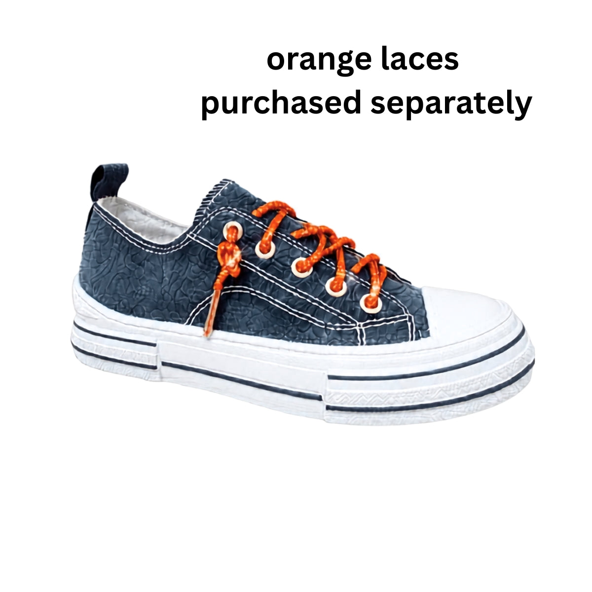 A Western-inspired sneaker from VERY G, the Aman Navy Tooled Sneakers feature a dark navy upper with intricate tooled floral detailing, a crisp white sole and toe, and eye-catching rhinestone shoelaces. Text above reads: “Rhinestone shoelaces purchased separately.”.