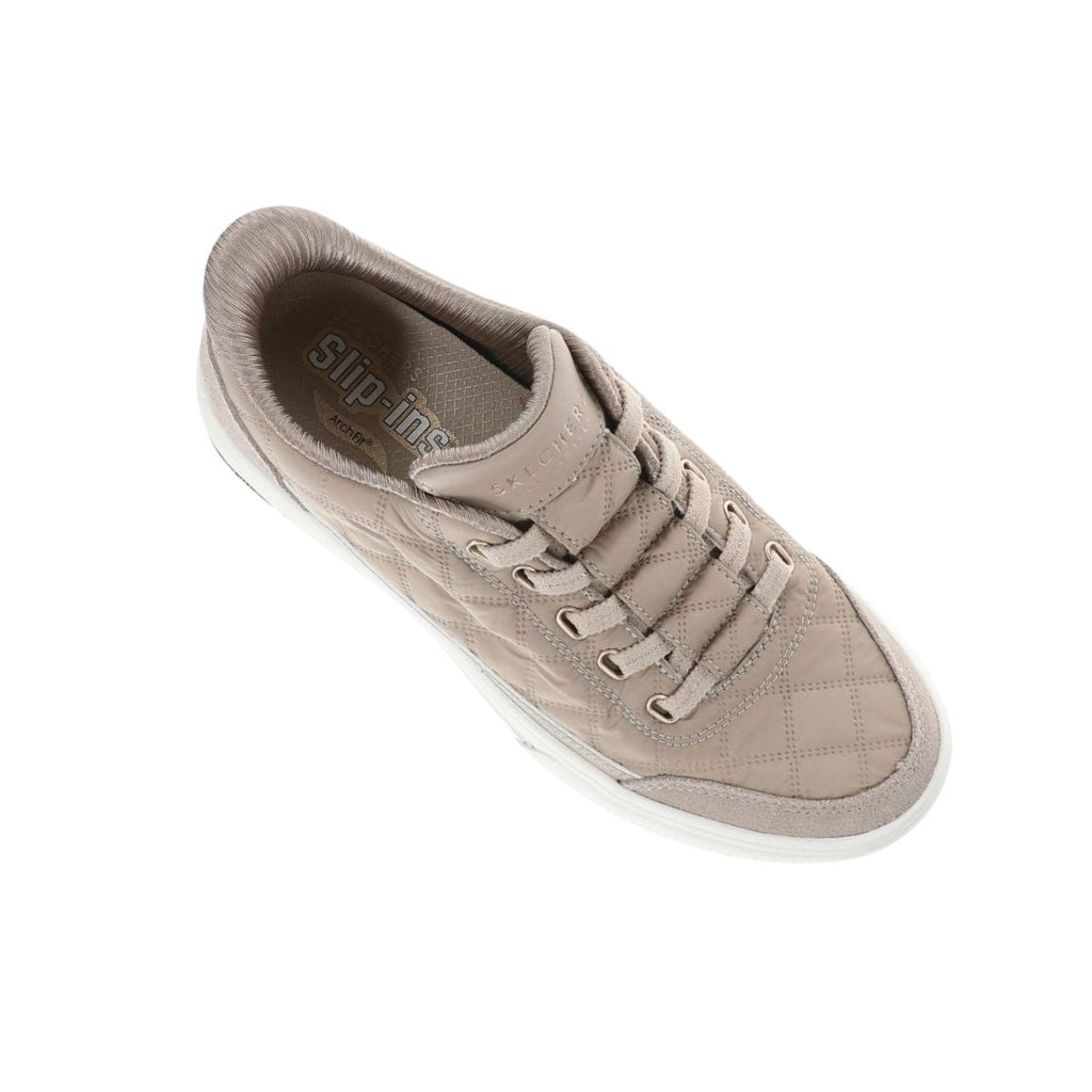Beige quilted SKECHERS USA INC Arch Fit Cuddle Steps Slip Ins sneaker with a white sole, shown from above. The insole displays “Slip-ins” and “Skechers,” emphasizing the Cozy Fit and Arch Fit support features.