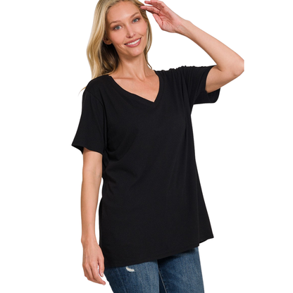 A woman smiles with one hand raised near her head, wearing a FASHION GO Boyfriend V-Neck Tee in black, made from 100% cotton, and blue jeans, standing against a white background.