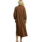 A woman with long blonde hair is shown from the back against a white background wearing the FASHION GO Striped Seersucker Midi Dress, a loose-fitting, brown striped midi dress with long sleeves.