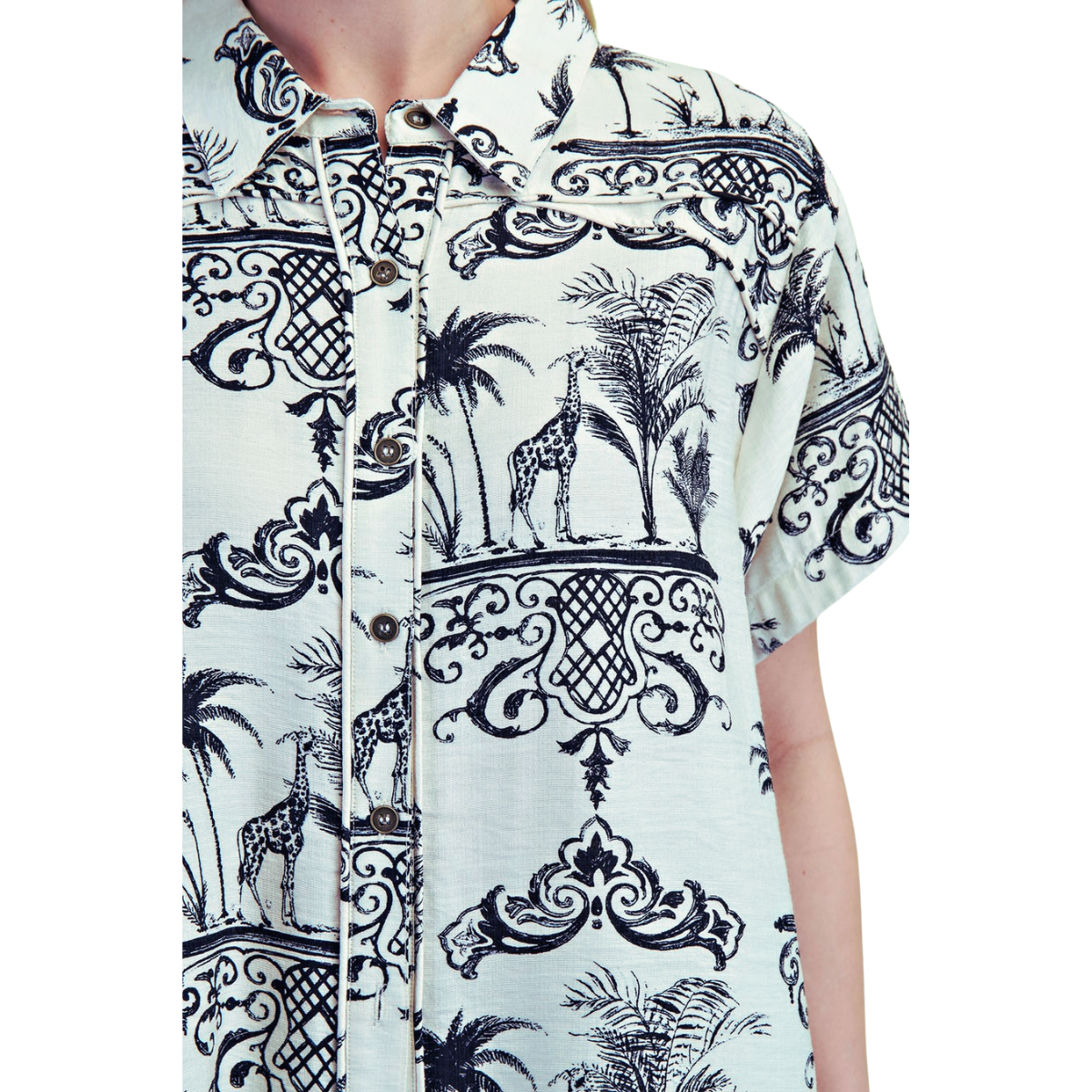 Someone wears the FASHION GO Toile Print 2 piece Set—a short-sleeve, button-up shirt and relaxed fit pants with a black and white giraffe, palm tree, and ornate pattern—for a comfortable yet stylish look.