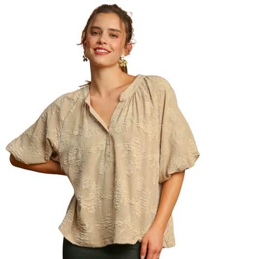 A woman models the Umgee Textured Floral Puff Sleeve Blouse, featuring a split neckline and short puff sleeves, against a white background.