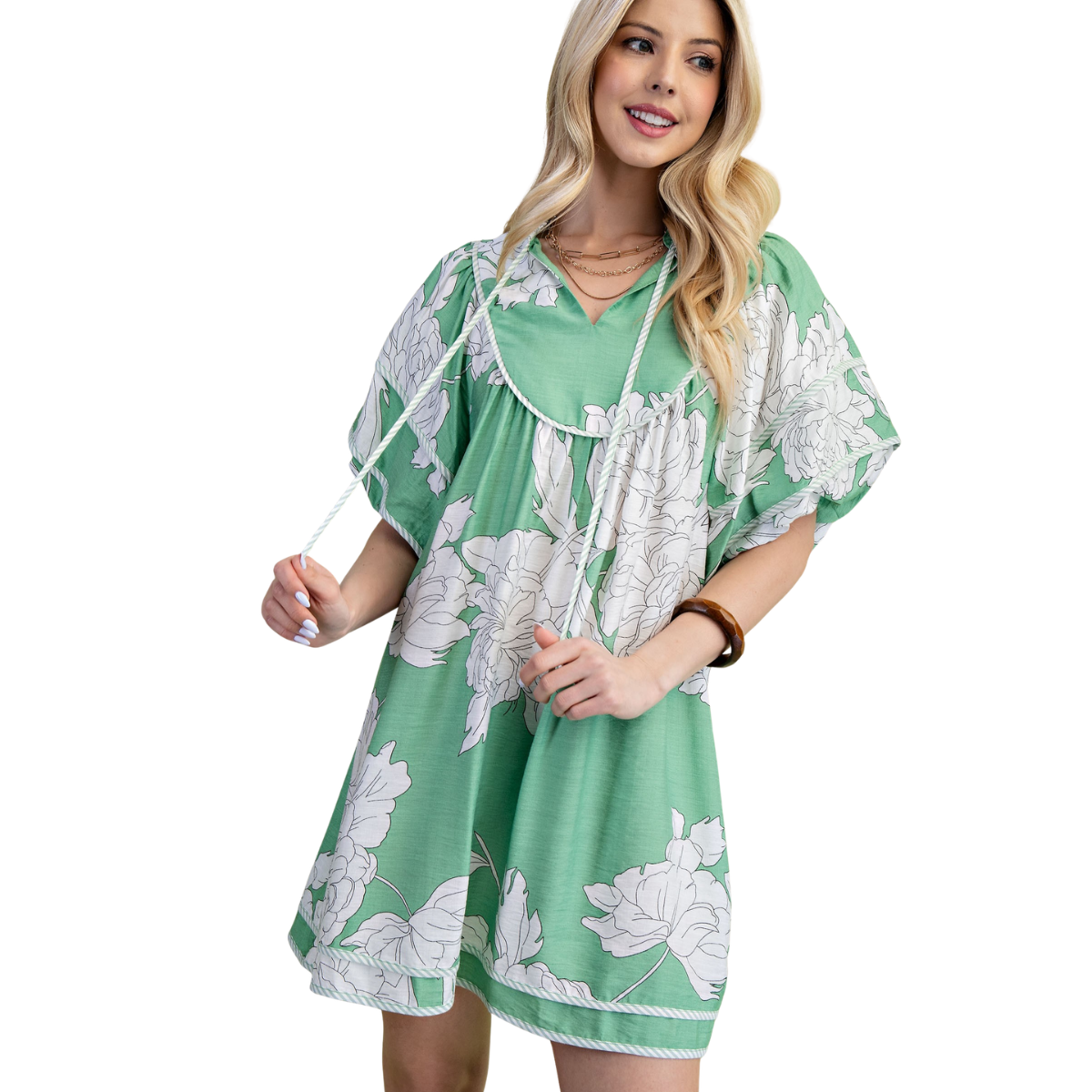 A woman wears the FASHION GO Floral Print Babydoll Dress, featuring a flowy green floral design, short sleeves, and a drawstring neckline, while standing and smiling. Main image