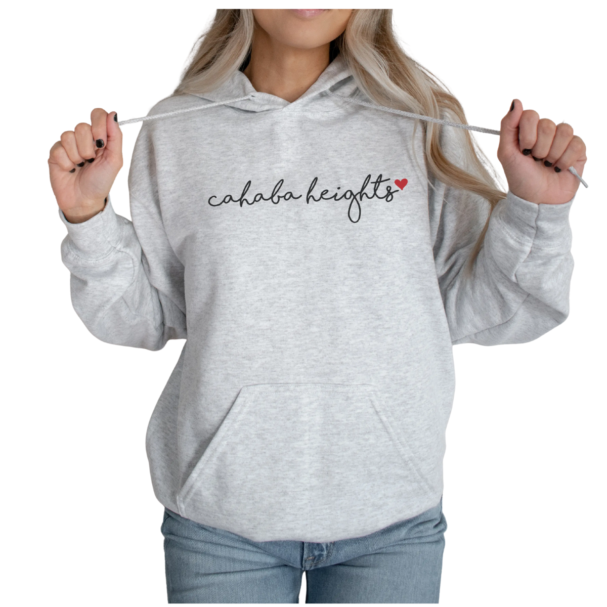A person wearing the Salt + Fare Cahaba Heights Hoodie in light gray, featuring "cahaba heights" in a local script and a small red heart on the front, holds the hoodie strings, shown from shoulders to hips.