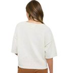 A person with long brown hair, shown from the back on a plain white background, wears the FASHION GO Raw Edge Boxy Short Sleeve Sweater in off-white paired with brown pants.