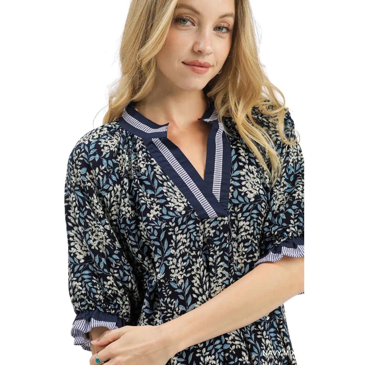 A woman stands with one arm crossed and a slight smile, wearing the Umgee Spring Burst Top in Navy Floral featuring puff sleeves and striped trim.