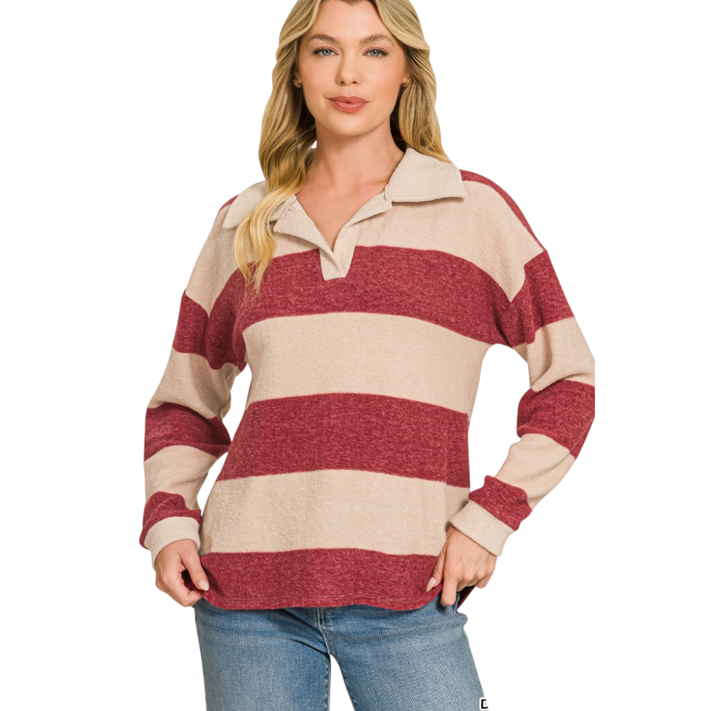 A woman stands against a white background with one hand on her hip, wearing the FASHION GO Brushed Hacci Collared Top—a cozy, lightweight red and beige striped sweater—paired with blue jeans.