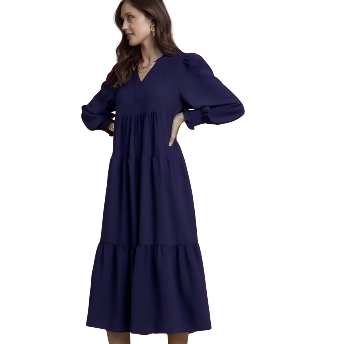 Woman wearing the Umgee Navy Tiered Midi Dress with Smocked Cuffs, featuring long sleeves and a split V-neck, standing with one hand on her hip against a white background.