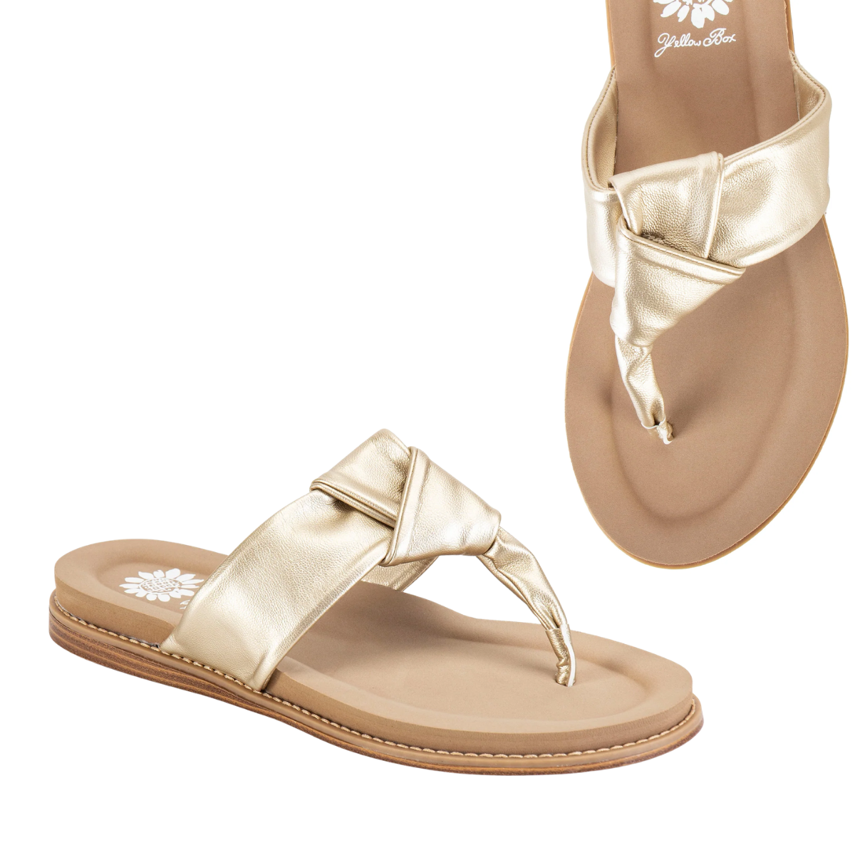 The Yellow Box Caine Flip Flop Sandal features gold metallic, buttery-soft faux leather knotted straps, a cushioned footbed, and a flat tan sole. Shown from side and top-down views. Main image