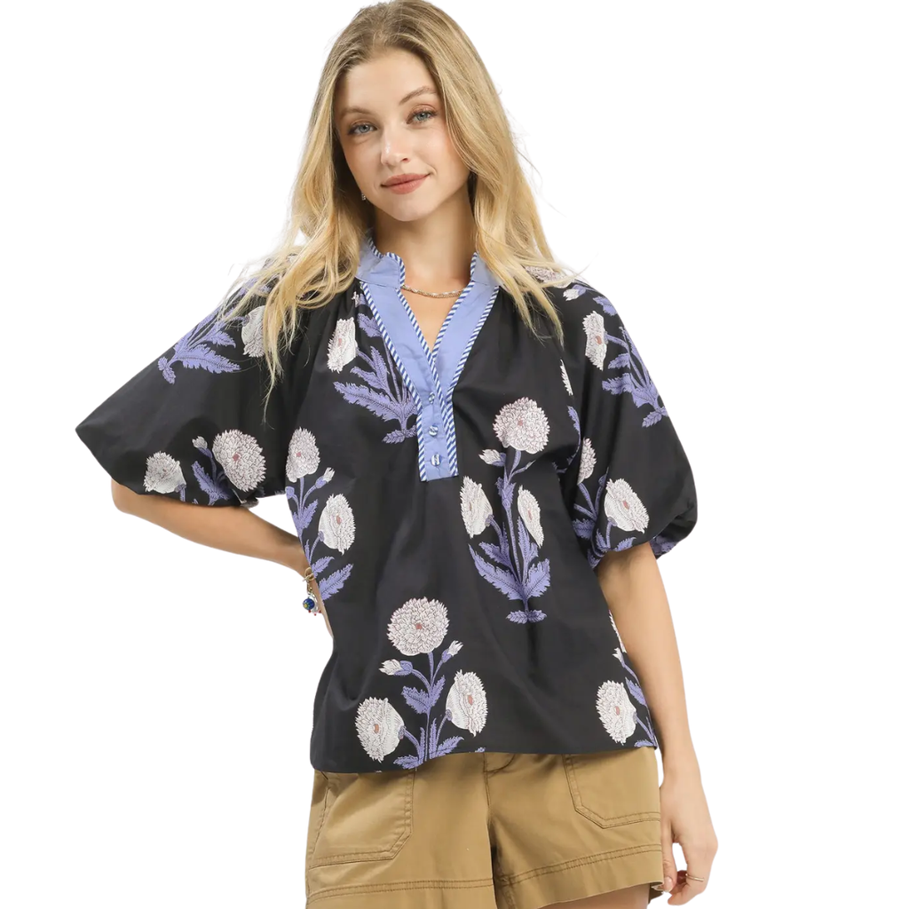 A woman models the Umgee Floral Print V-Neck Top with floral embroidery, pairing it with tan shorts against a white background to showcase its lightweight cotton style.