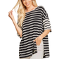A woman smiles warmly as she holds a strand of hair, wearing a FASHION GO Striped T shirt Top—black and white stripes, short sleeves—paired with light-colored pants.